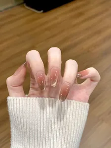 Gros plan sur des ongles press-on dégradés ambrés oeil-de-chat en forme ovale longue