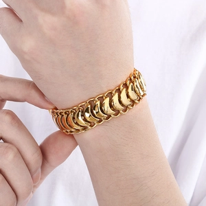 Close-up of a wide polished gold keel link bracelet worn on a man's wrist in hip-hop style