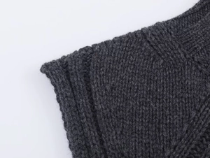 Detailed close-up of dark grey wool blend knit fabric showing ribbed textures and seams