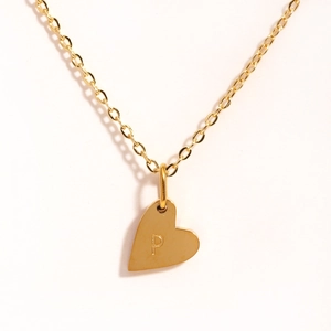 Gros plan d'un collier pendentif coeur doré avec lettre P gravée sur une chaîne fine