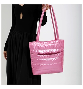 Pink quilted tote bag with metallic finish and long handles shown with model
