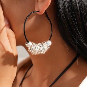Detail shot of a black hoop earring with silver charms and faux pearls on a model