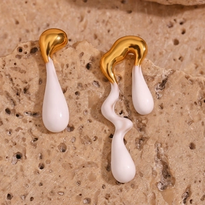 Detail of asymmetric white enamel and 18K gold plated lava earrings on stone