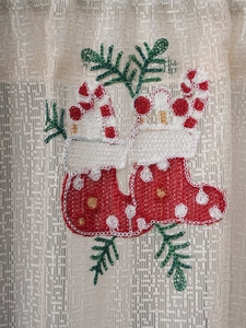 Detailed close-up of festive Christmas embroidery on white mesh lace curtain fabric