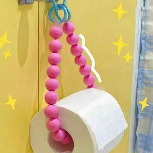 Detail of pink beaded toilet paper holder with blue ring on vibrant yellow background