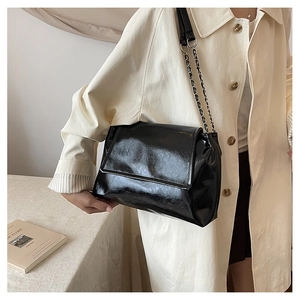 French style black patent leather shoulder bag with chain strap shown on person