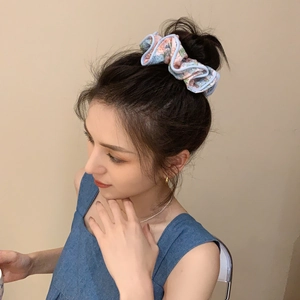 Floral print scrunchie in blue and pink tones styled on a bun for a soft summer look