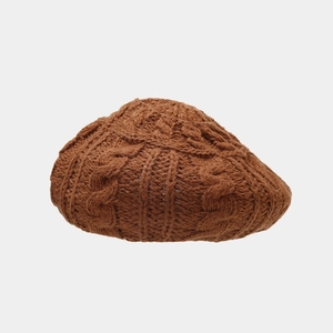 Detailed view of brown cable-knit beret hat featuring thick wool texture and intricate weave