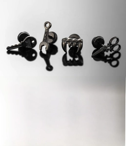 Macro detail of black titanium steel stud earrings in key, wrench and scissor shapes
