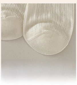 Detail showing smooth seamless toe stitching and ribbed knit texture on cream crew socks