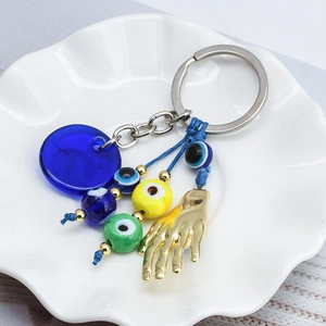 Blue Evil Eye keychain with Fatima hand charm and colorful beads on white ceramic tray