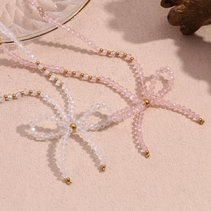 Detailed macro view of beaded necklace featuring pink crystals and golden bow design