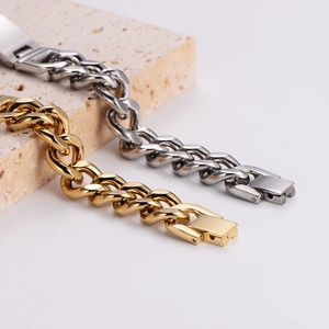 Polished gold and silver Cuban link bracelets displayed on minimalist stone props
