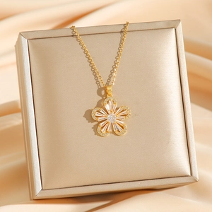 Golden five-petal flower necklace with zircon pavé on a gift box with satin background