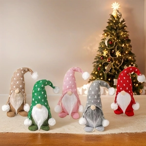 Detailed view of five colorful knit Christmas gnomes arranged by a lit holiday tree