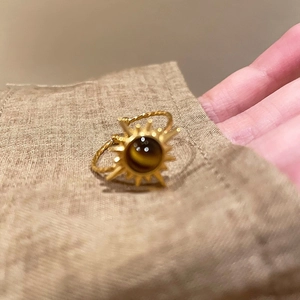 Macro view of vintage gold sunburst ring with tiger eye stone on textured fabric