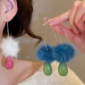 Dettaglio di orecchini a goccia eleganti con pompon in pelliccia e ganci dorati
