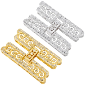 Macro detail of H-shaped gold plated clasp with cubic zirconia and filigree pattern