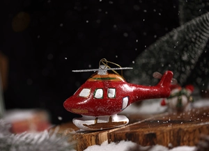 Detail of red helicopter Christmas tree ornament on rustic wood with a snowy background