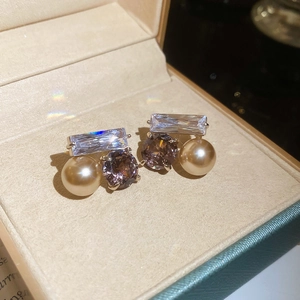 Vue détaillée de boucles d'oreilles avec zircone et perle champagne sur velours