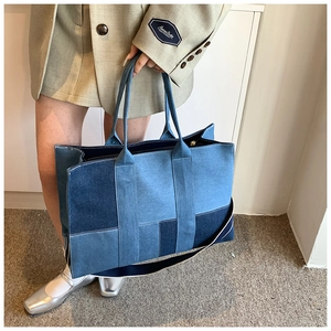 Detail of multi-tone blue patchwork denim tote bag showing stitching and fabric texture