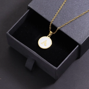 Detail of 18k gold plated shell pendant with letter A in a black drawer gift box