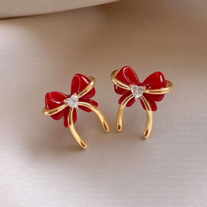 Macro shot of red enamel bow earrings with a heart-shaped stone on a gold-plated base