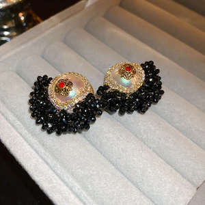 Close-up of vintage black beaded earrings with crystal accents and gold-white floral center