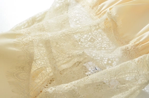 Gros plan sur le tissu en soie beige et la dentelle délicate de cette robe d'été