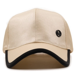 Detail of satin baseball cap featuring champagne silk texture and black M metal emblem
