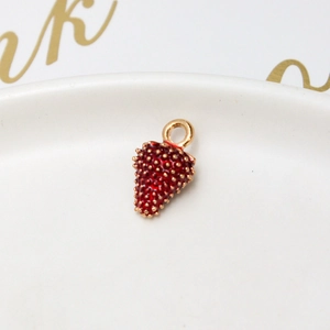 Macro shot of a red strawberry alloy pendant with gold dots for DIY jewelry making
