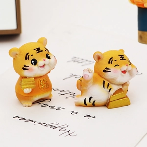 Close-up of cute orange resin tiger figurines with lucky gold ingots and Fu symbol