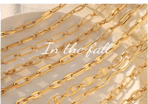 Detail of 18K gold plated geometric chain link jewelry set on white ceramic tray