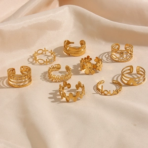 Set of 9 gold-plated stainless steel open rings with floral and leaf motifs on beige silk