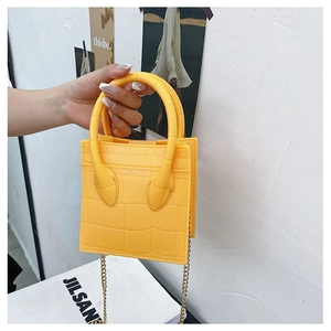 Detail of yellow crocodile embossed mini bag with gold chain strap and handles