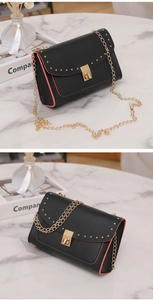 Detail of black rivet bag with pink edges and gold chain strap on marble