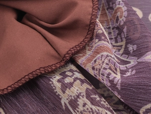 Detail shot of brown lining and purple paisley chiffon fabric with high-quality stitching