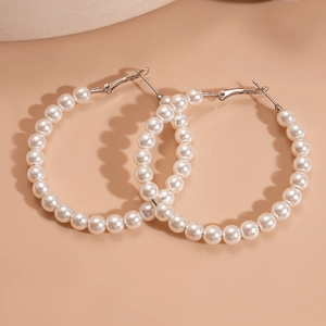 Macro view of white faux pearl hoop earrings showing elegant beaded circular design
