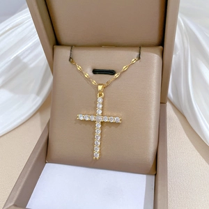 Exquisite gold-plated cross pendant necklace with zircon stones on a white silk background