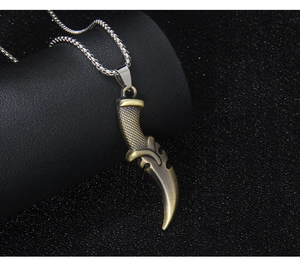 Detail shot of a bronze dagger pendant on a black leather display and silver chain