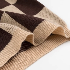 Detailed macro view of the checkered knit sweater hem showing the ribbed edge texture