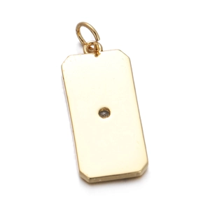 Close-up of golden rectangular metal pendant with a small sparkling zircon stone