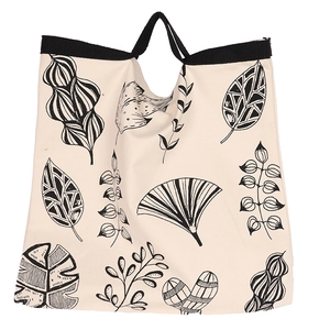Detail of minimalist canvas tote bag featuring black leaf patterns and sturdy black straps