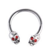 Macro shot of horseshoe piercing ring featuring silver skull ends and red crystal eyes