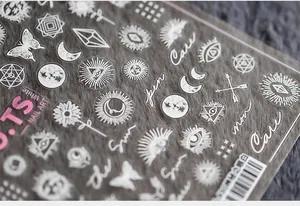 Macro shot of 5D white nail art stickers with mystic eye, moon, and sun patterns