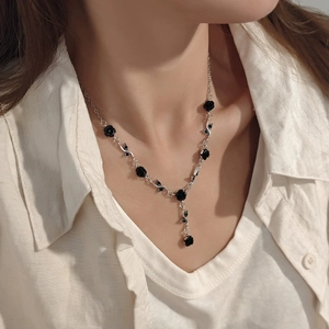 Detail of a vintage-style black rose necklace with silver chain on model neck