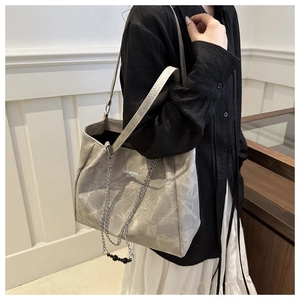 Light gray chain tote bag shown on shoulder, highlighting spacious capacity and modern style