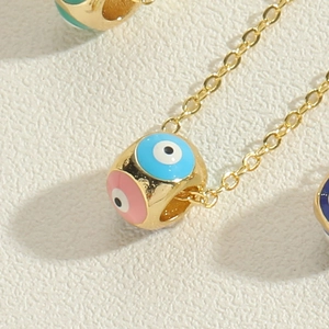 Macro shot of gold-plated evil eye cylinder pendant with colorful enamel details