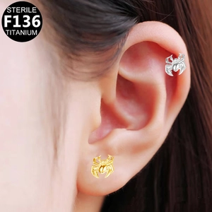 Macro shot of spider shaped F136 titanium studs on ear cartilage and lobe piercings