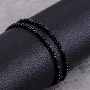 Macro view of black square link chain with metallic luster on industrial background